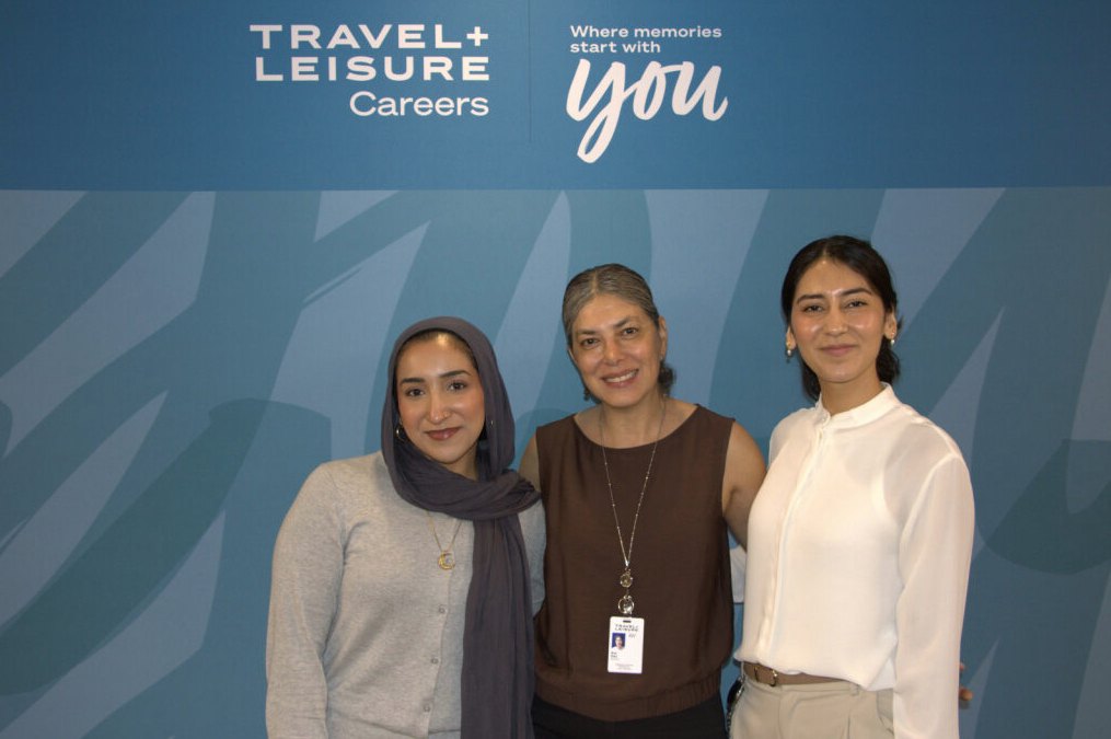 Three colleagues smiling in front of a Travel + Leisure Careers backdrop that reads “Where memories start with you”